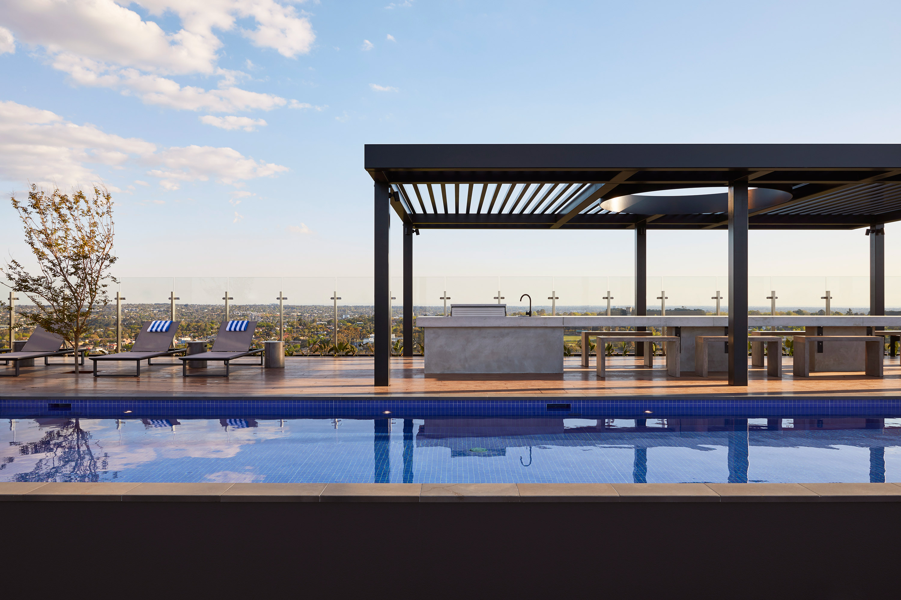 A rooftop pool with a rectangular awning over a deck